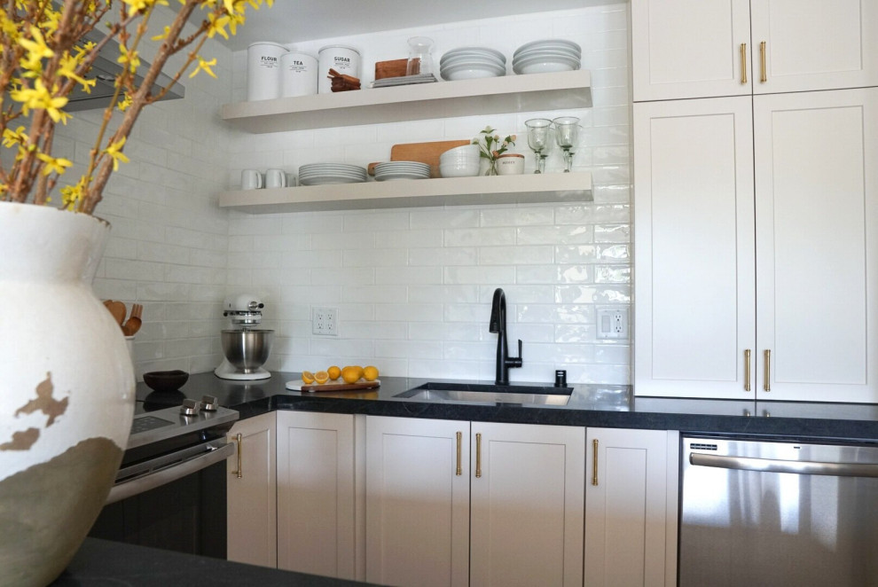 Inspiration for a small transitional u-shaped eat-in kitchen in Philadelphia with an undermount sink, shaker cabinets, beige cabinets, soapstone benchtops, white splashback, subway tile splashback, stainless steel appliances, vinyl floors, a peninsula, beige floor and black benchtop.