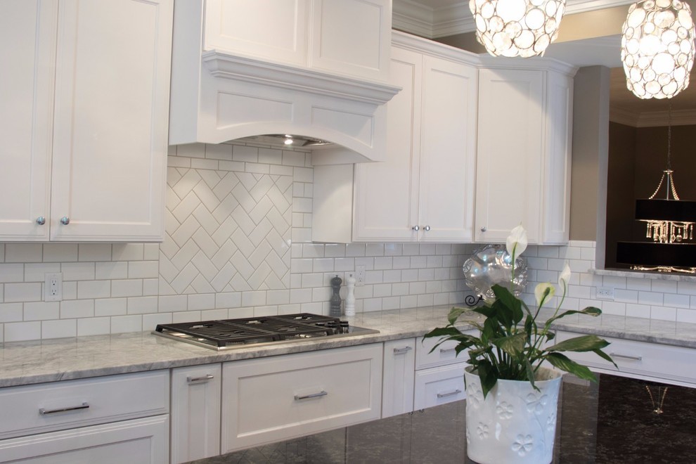 Large transitional u-shaped eat-in kitchen in Cincinnati with a farmhouse sink, recessed-panel cabinets, white cabinets, granite benchtops, white splashback, subway tile splashback, panelled appliances, medium hardwood floors and multiple islands.