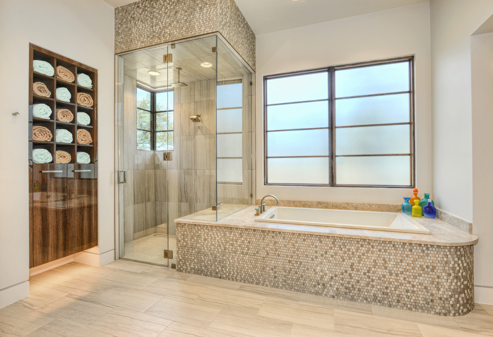 Photo of a large modern master bathroom in Houston with flat-panel cabinets, brown cabinets, a drop-in tub, a corner shower, a wall-mount toilet, gray tile, ceramic tile, grey walls, ceramic floors, an undermount sink, marble benchtops, beige floor, a hinged shower door and beige benchtops.