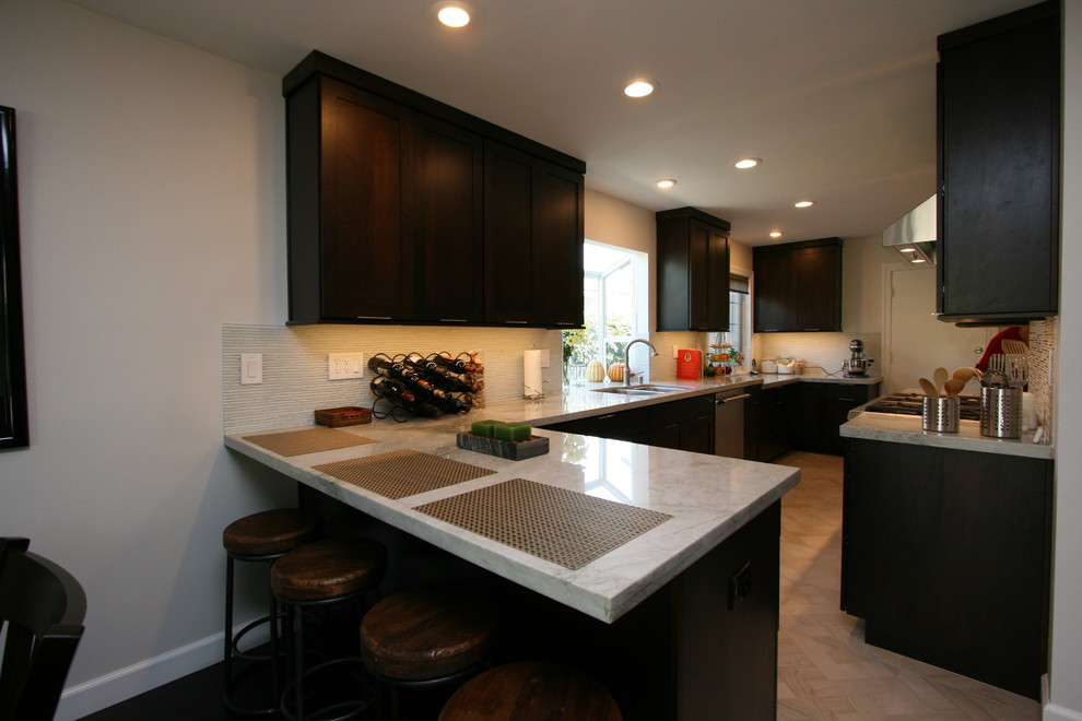 Inspiration for a mid-sized transitional l-shaped porcelain tile kitchen remodel in Orange County with a double-bowl sink, recessed-panel cabinets, dark wood cabinets, quartzite countertops, white backsplash, glass tile backsplash, stainless steel appliances and no island