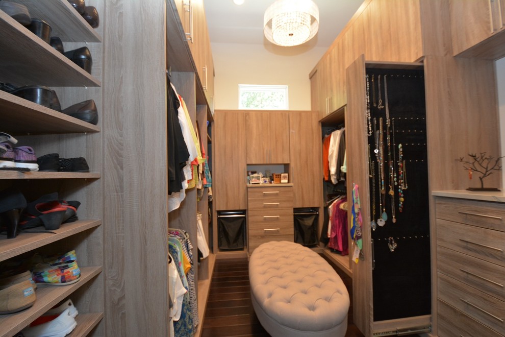 This is an example of a large contemporary women's walk-in wardrobe in Tampa with flat-panel cabinets, light wood cabinets and dark hardwood floors.