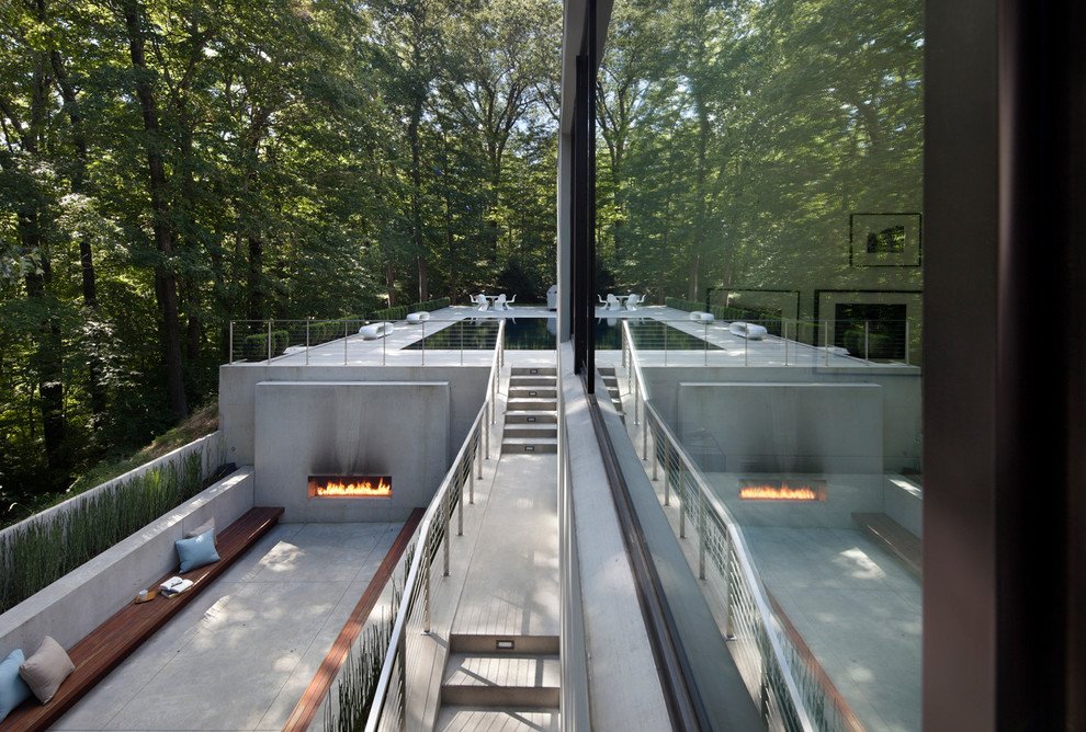 This is an example of a large modern courtyard patio in New York with a fire feature, concrete slab and no cover.