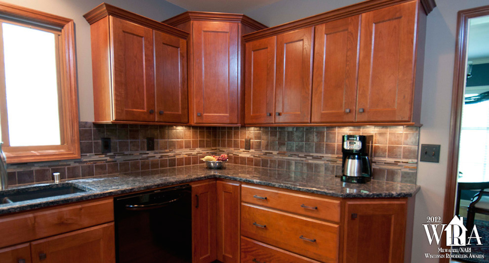 Inspiration for a transitional l-shaped medium tone wood floor eat-in kitchen remodel in Milwaukee with an undermount sink, recessed-panel cabinets, dark wood cabinets, granite countertops, gray backsplash, porcelain backsplash, stainless steel appliances and an island