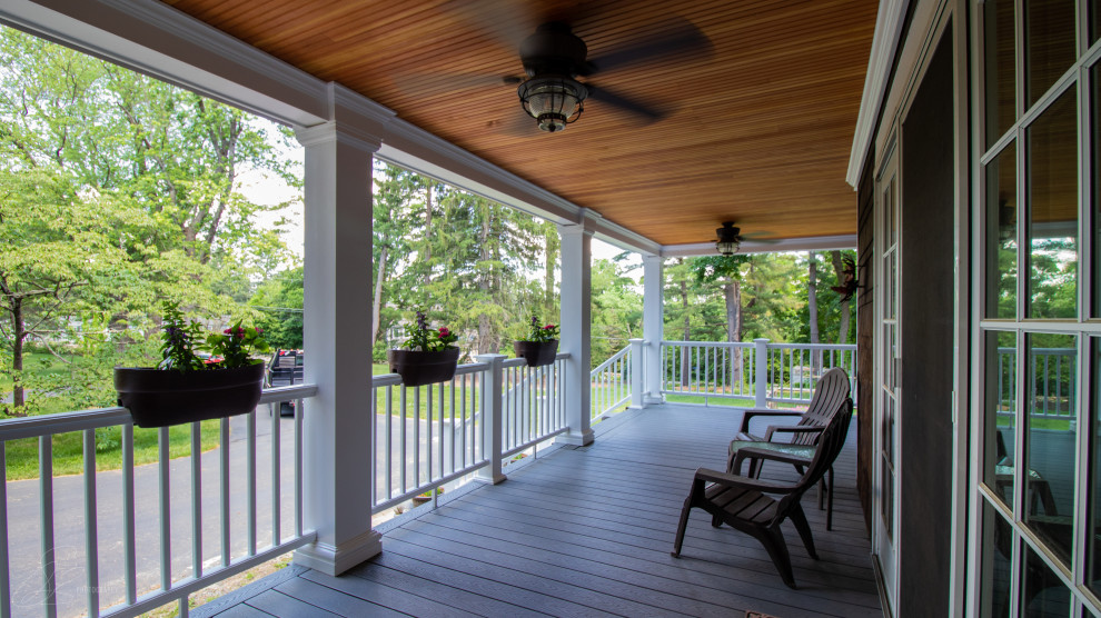 This is an example of a large arts and crafts front yard verandah in Boston with with columns, decking and a roof extension.