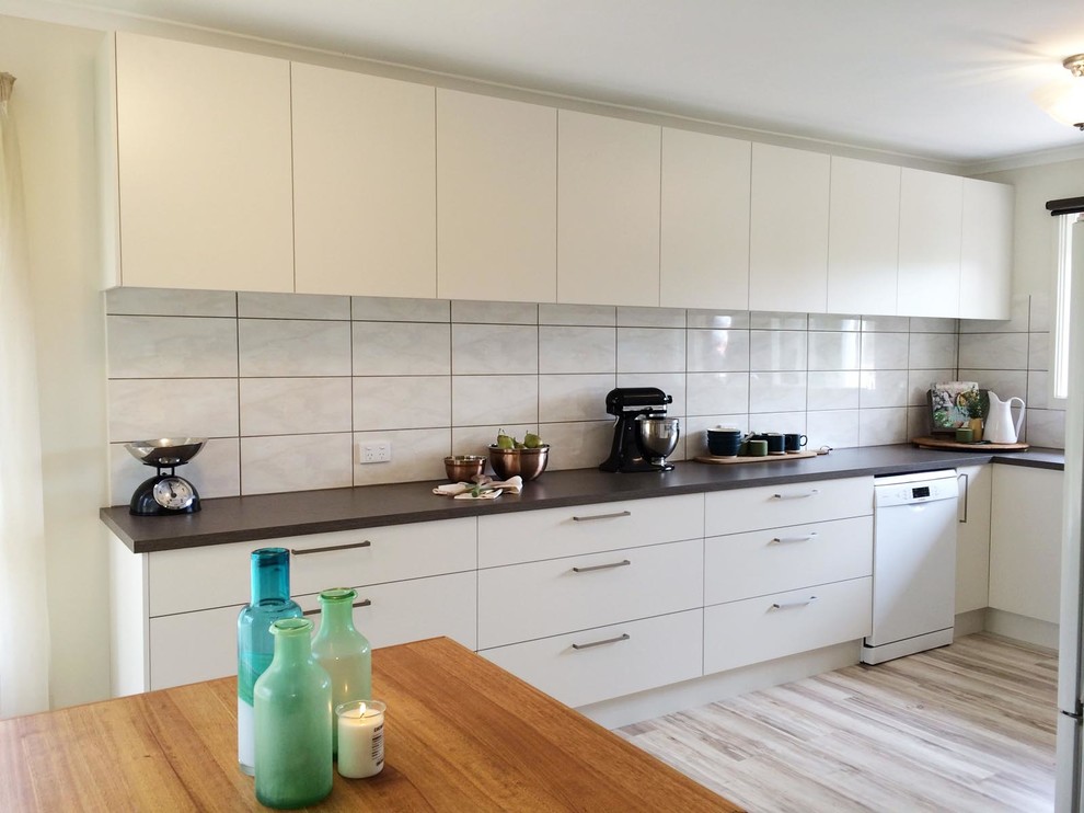 Mid-sized transitional u-shaped eat-in kitchen in Melbourne with a double-bowl sink, flat-panel cabinets, white cabinets, laminate benchtops, beige splashback, ceramic splashback, white appliances and no island.