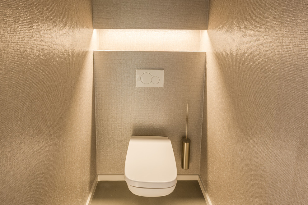Small modern powder room in Other with a wall-mount toilet, beige tile, mosaic tile, beige walls, concrete floors, a pedestal sink, solid surface benchtops and grey floor.