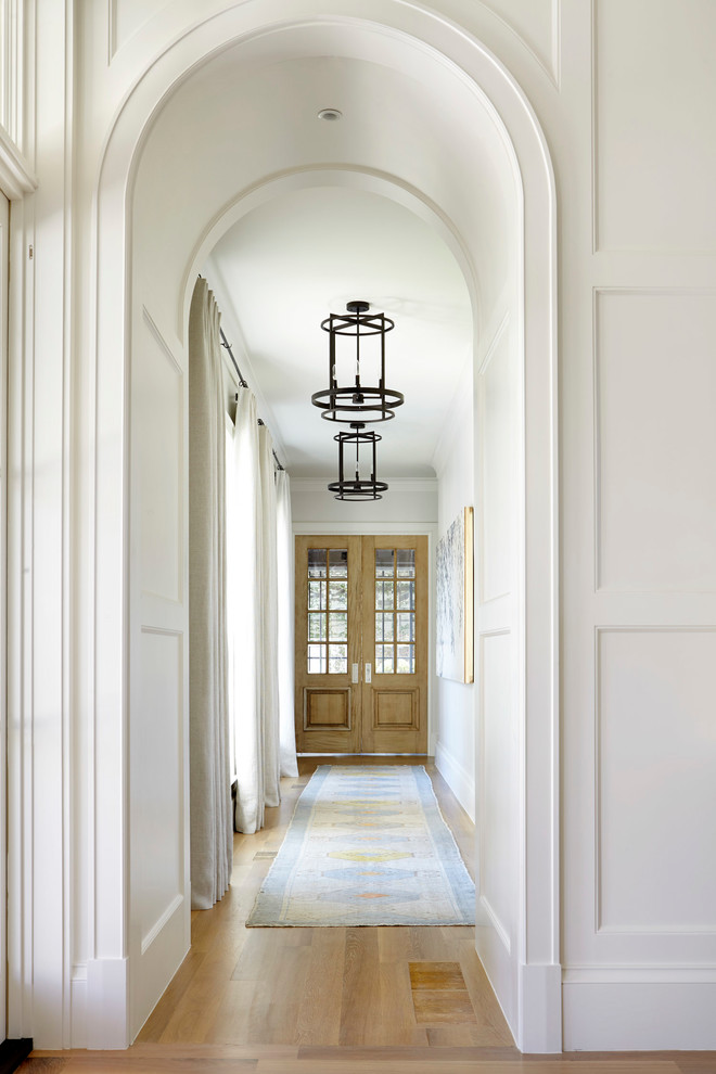 Photo of a transitional hallway in Dallas with white walls, medium hardwood floors and brown floor.