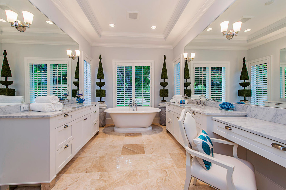 This is an example of a transitional bathroom in Miami with a freestanding tub and marble benchtops.