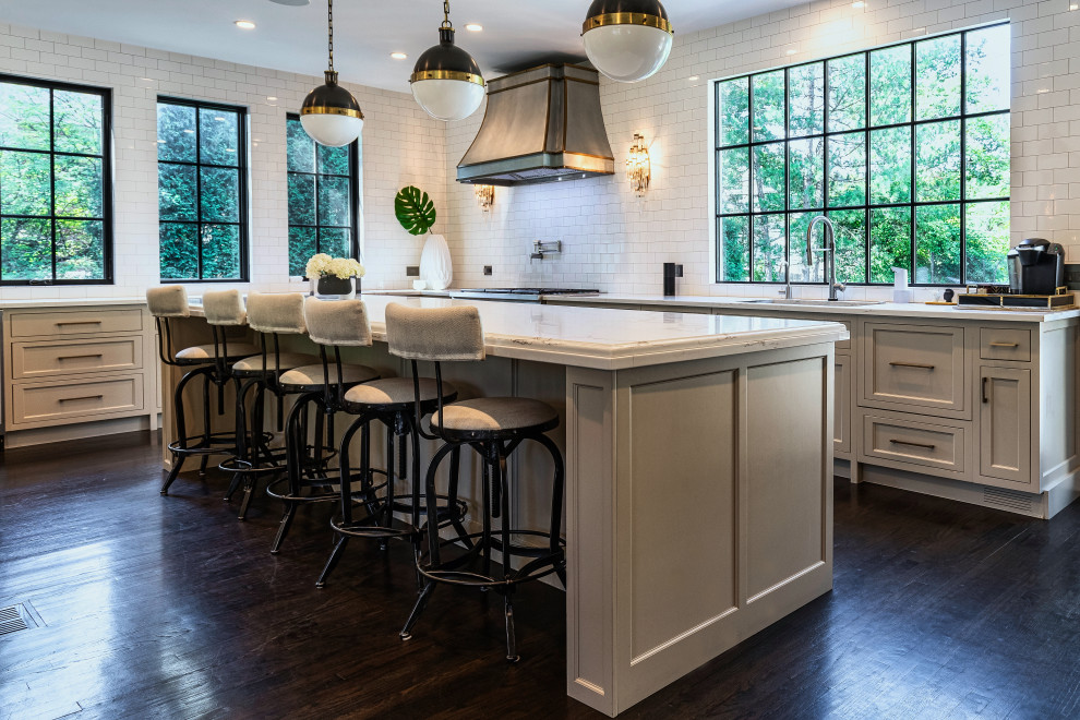 This is an example of a large classic l-shaped kitchen in Chicago with a submerged sink, beaded cabinets, beige cabinets, engineered stone countertops, white splashback, porcelain splashback, stainless steel appliances, dark hardwood flooring, an island, brown floors and white worktops.