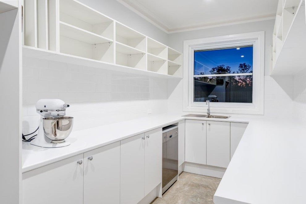 Design ideas for a contemporary u-shaped kitchen pantry in Sydney with a double-bowl sink, white cabinets, laminate benchtops, white splashback, ceramic splashback and stainless steel appliances.