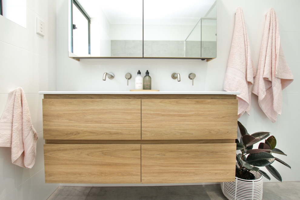 Photo of a small scandinavian master bathroom in Sydney with light wood cabinets, a corner tub, a corner shower, an integrated sink, a hinged shower door, white benchtops, a double vanity and a floating vanity.