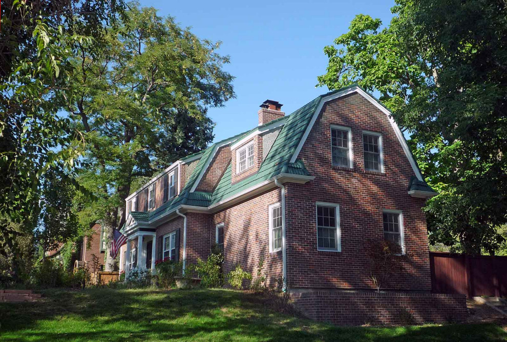 Cette photo montre une façade de maison chic en brique à un étage avec un toit de Gambrel et un toit en tuile.