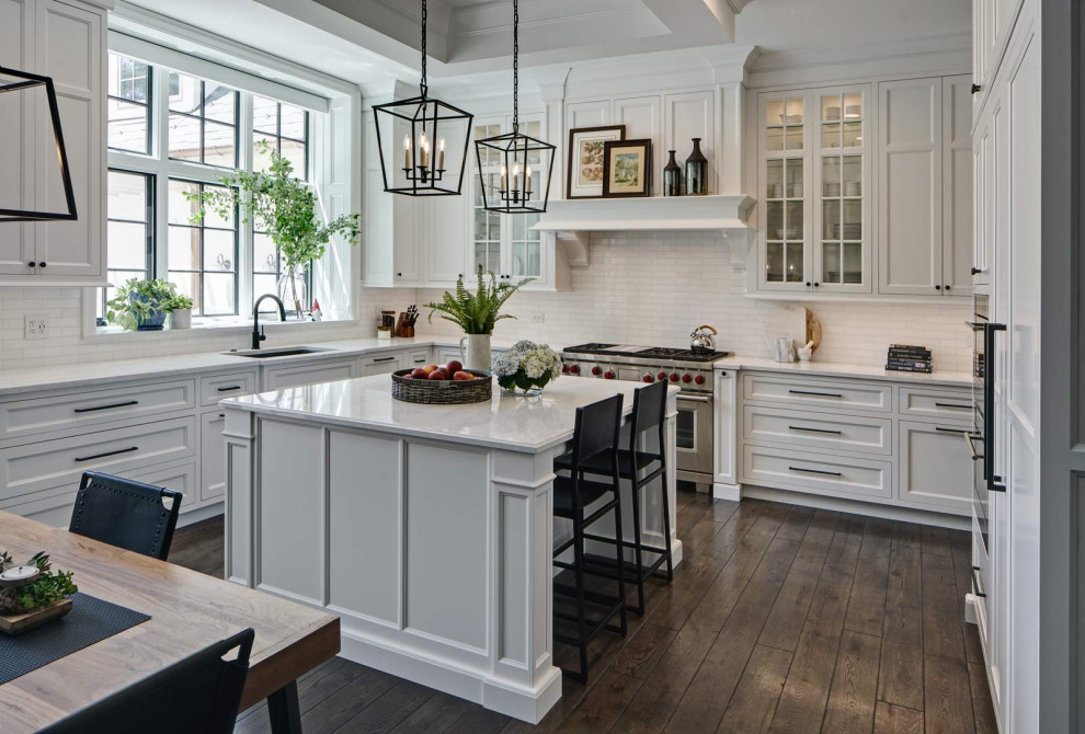 Inspiration for a large transitional l-shaped dark wood floor, brown floor and tray ceiling eat-in kitchen remodel in Chicago with an undermount sink, recessed-panel cabinets, white cabinets, quartzite countertops, white backsplash, ceramic backsplash, stainless steel appliances, an island and white countertops
