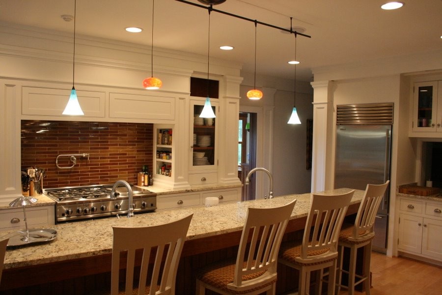 This is an example of a large beach style eat-in kitchen in Atlanta with stainless steel appliances, recessed-panel cabinets, white cabinets, granite benchtops, multi-coloured splashback, light hardwood floors and with island.