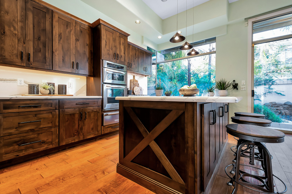 Example of a large transitional u-shaped open concept kitchen design in Phoenix with a farmhouse sink, shaker cabinets, dark wood cabinets, quartz countertops, white backsplash, quartz backsplash, stainless steel appliances, an island and white countertops