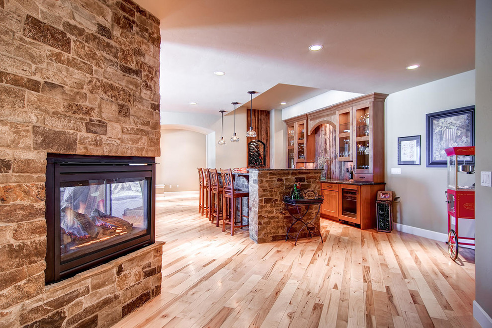 Large traditional walk-out basement in Denver with beige walls, light hardwood floors, a two-sided fireplace and a brick fireplace surround.