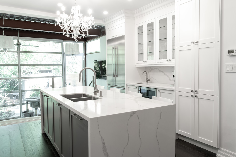 Inspiration for a mid-sized modern galley open plan kitchen in Toronto with an undermount sink, shaker cabinets, white cabinets, quartz benchtops, white splashback, stone slab splashback, stainless steel appliances, dark hardwood floors, with island, brown floor and white benchtop.