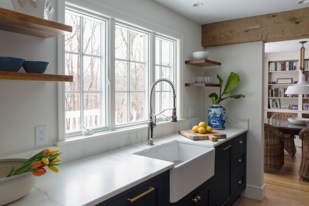 Example of a small transitional u-shaped marble floor, beige floor and exposed beam eat-in kitchen design in New York with a farmhouse sink, shaker cabinets, blue cabinets, marble countertops, white backsplash, ceramic backsplash, paneled appliances, no island and white countertops