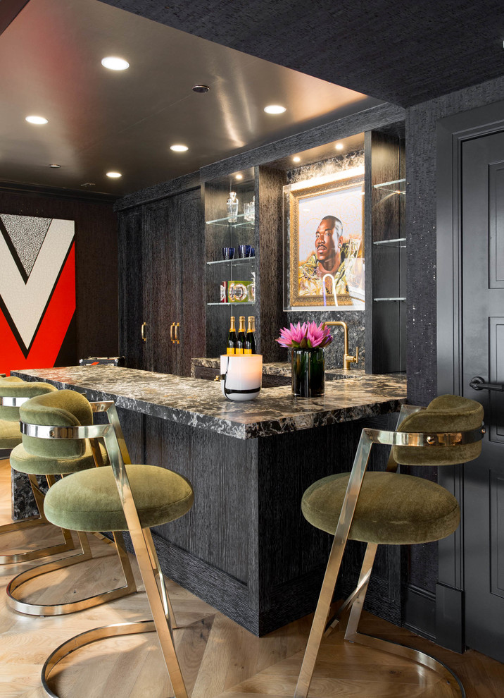 Photo of an eclectic u-shaped seated home bar in New York with black cabinets, light hardwood floors and shaker cabinets.