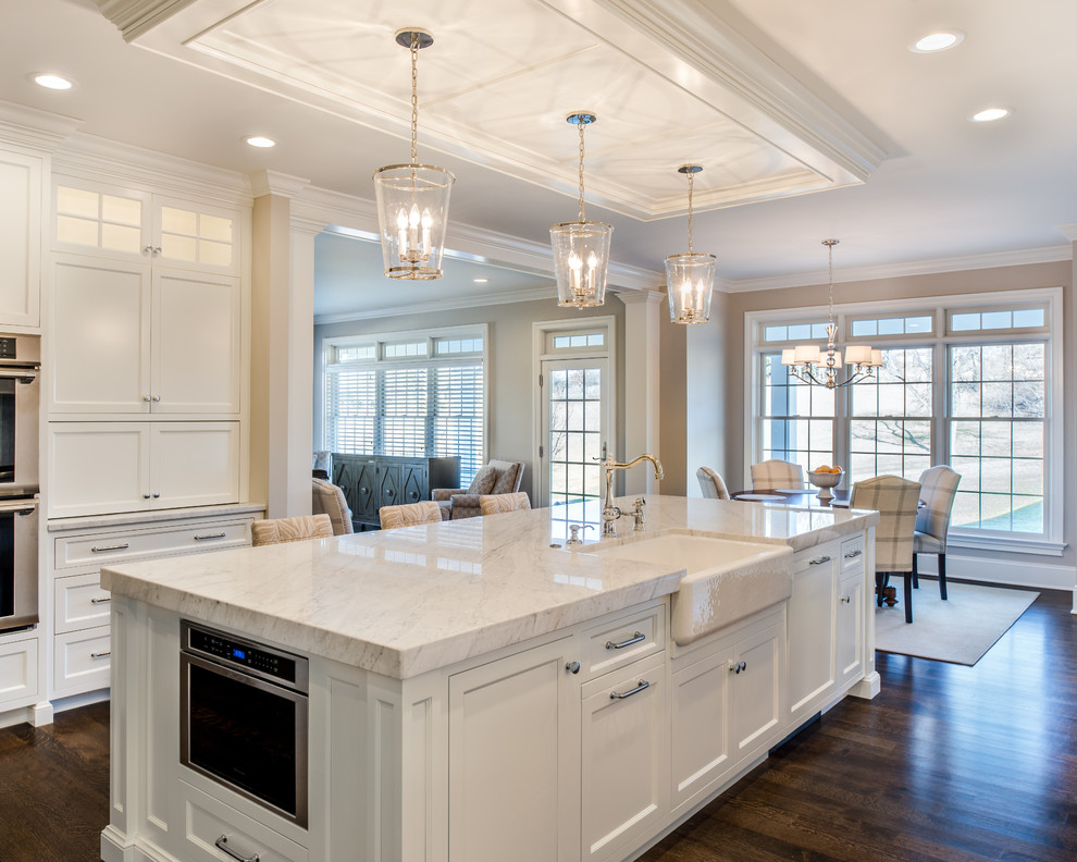 Expansive transitional single-wall eat-in kitchen in Philadelphia with a farmhouse sink, recessed-panel cabinets, white cabinets, marble benchtops, panelled appliances, dark hardwood floors and with island.