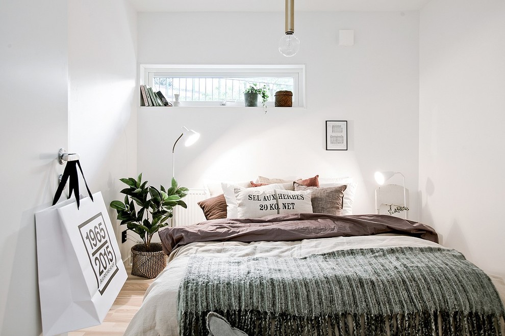 Photo of a mid-sized scandinavian master bedroom in Gothenburg with white walls and light hardwood floors.