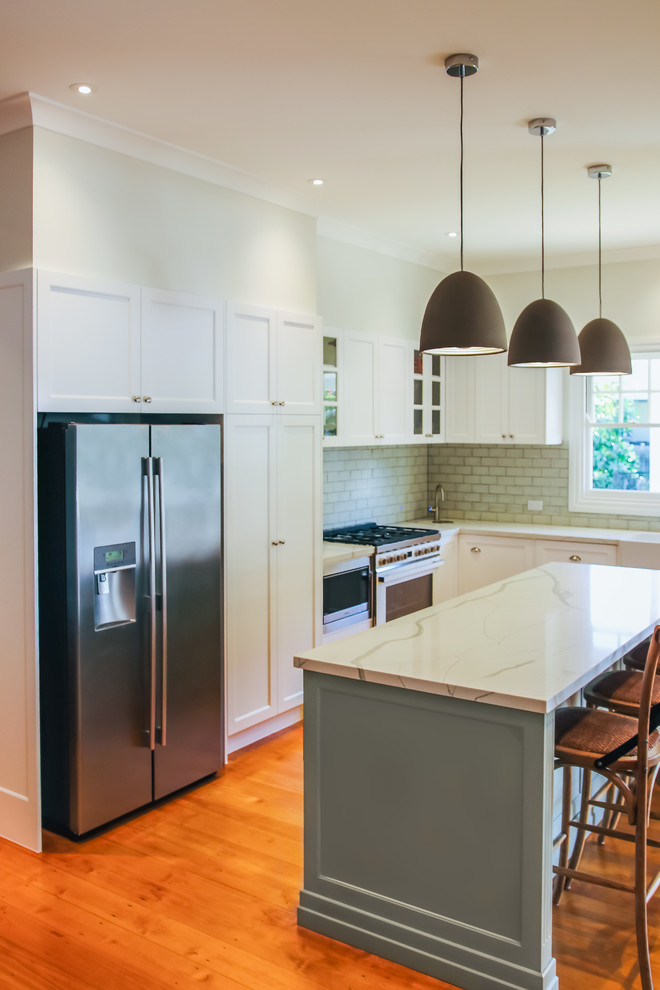 Design ideas for a large traditional l-shaped eat-in kitchen in Brisbane with a farmhouse sink, shaker cabinets, green cabinets, quartz benchtops, green splashback, subway tile splashback, white appliances, medium hardwood floors, with island and green benchtop.