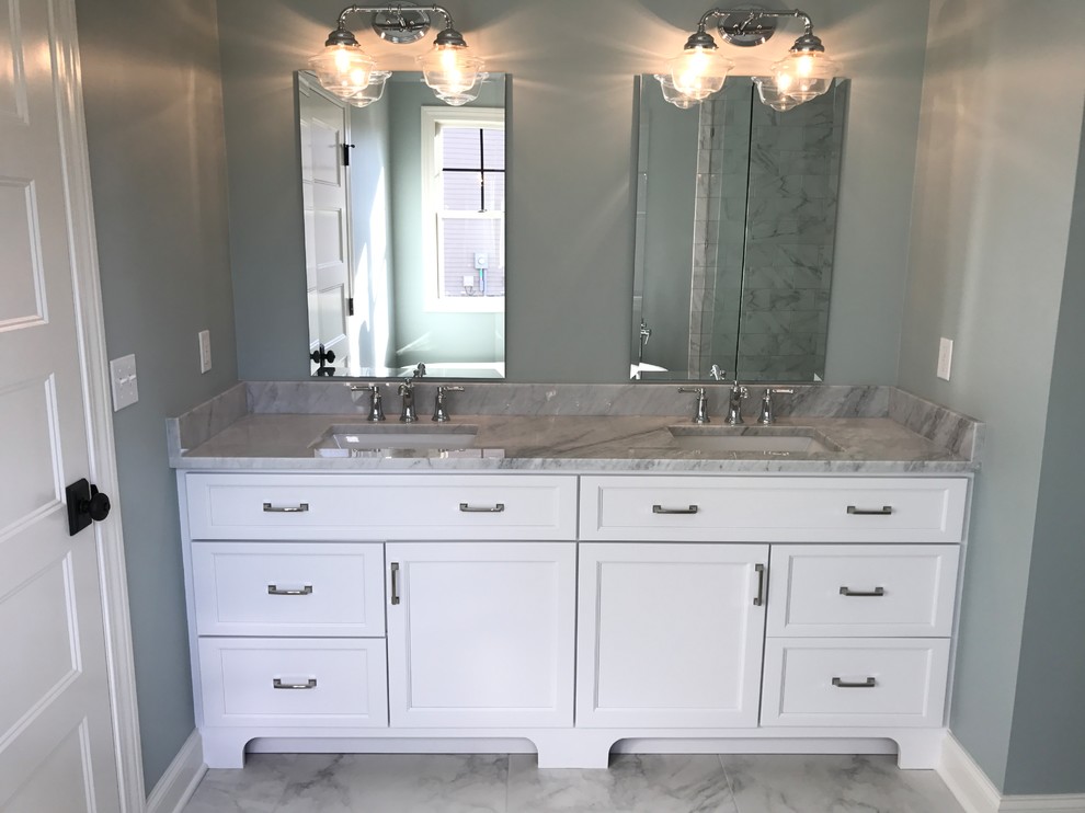 Cette image montre une grande salle de bain principale design avec un placard à porte shaker, des portes de placard blanches, un mur gris, un sol en carrelage de porcelaine, un lavabo encastré, un plan de toilette en marbre et un sol gris.