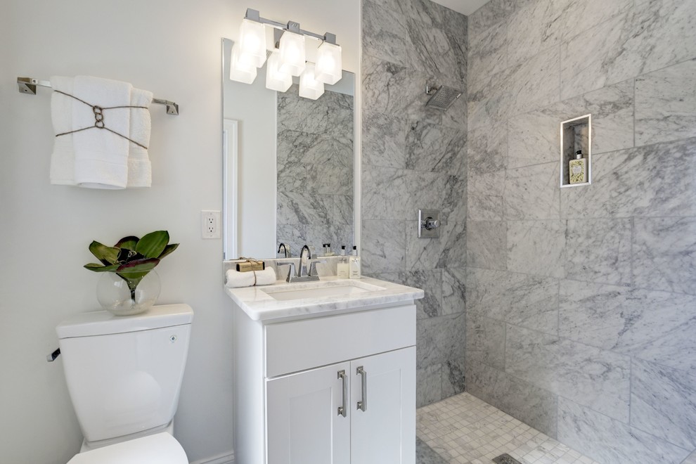 This is an example of a transitional bathroom in DC Metro with shaker cabinets, white cabinets, an open shower, a two-piece toilet, gray tile, white tile, white walls, an undermount sink and an open shower.