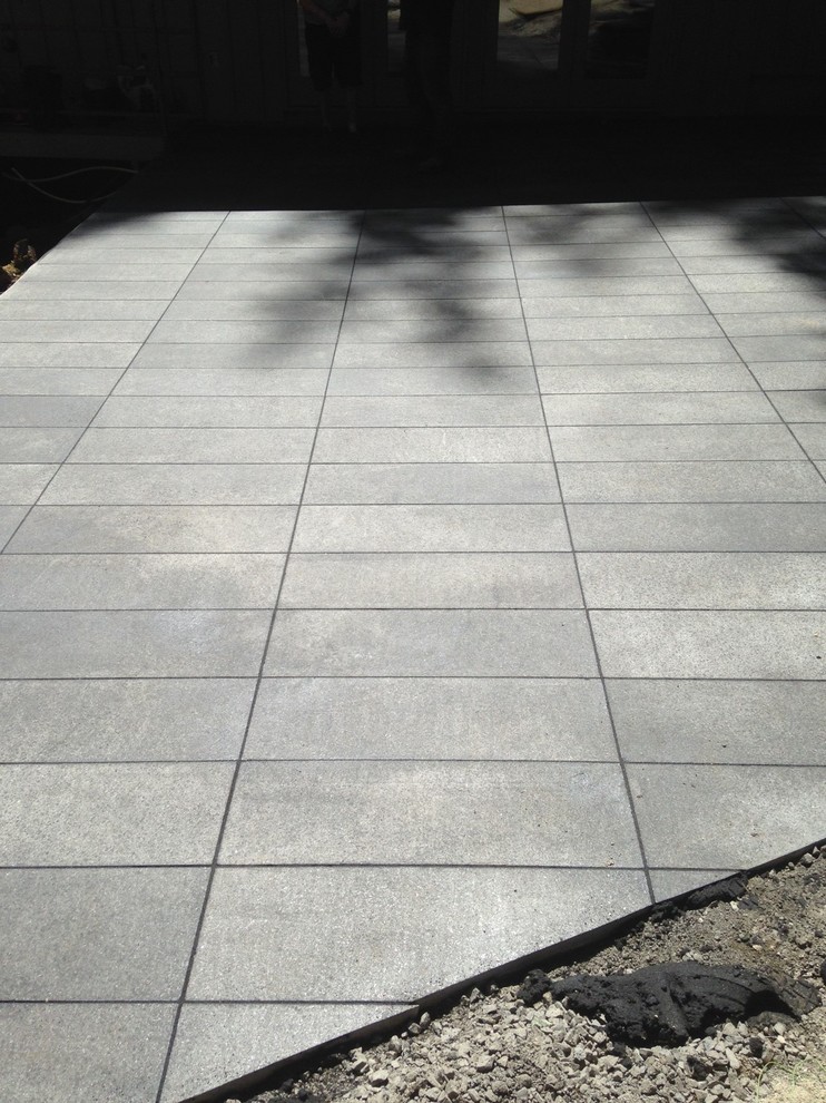 Mid-sized midcentury backyard patio in Vancouver with natural stone pavers.