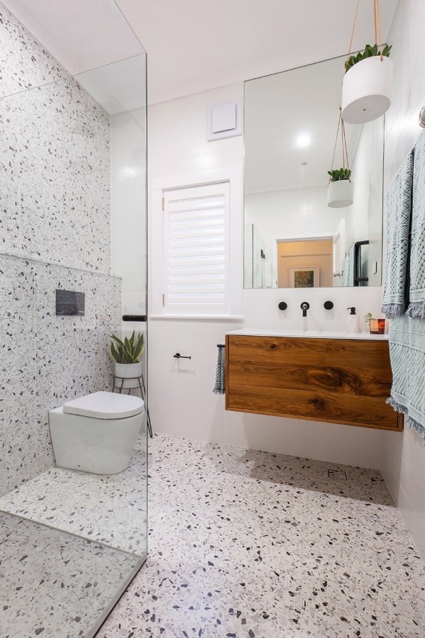 Inspiration for a mid-sized modern 3/4 wet room bathroom in Sydney with furniture-like cabinets, dark wood cabinets, a wall-mount toilet, black and white tile, stone tile, white walls, terrazzo floors, an integrated sink, engineered quartz benchtops, multi-coloured floor, a hinged shower door and white benchtops.