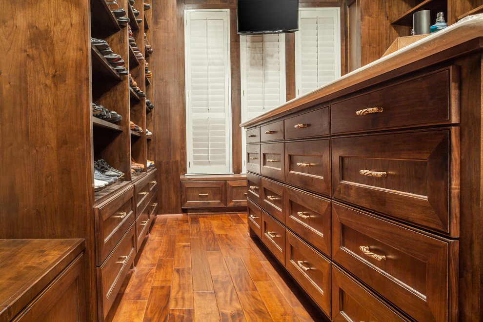 Design ideas for a large traditional gender-neutral dressing room in Houston with recessed-panel cabinets, dark wood cabinets and medium hardwood floors.