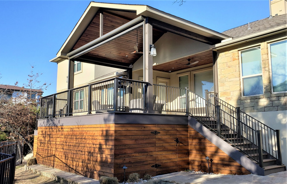 Inspiration for a large country backyard and first floor deck in Austin with a roof extension and metal railing.