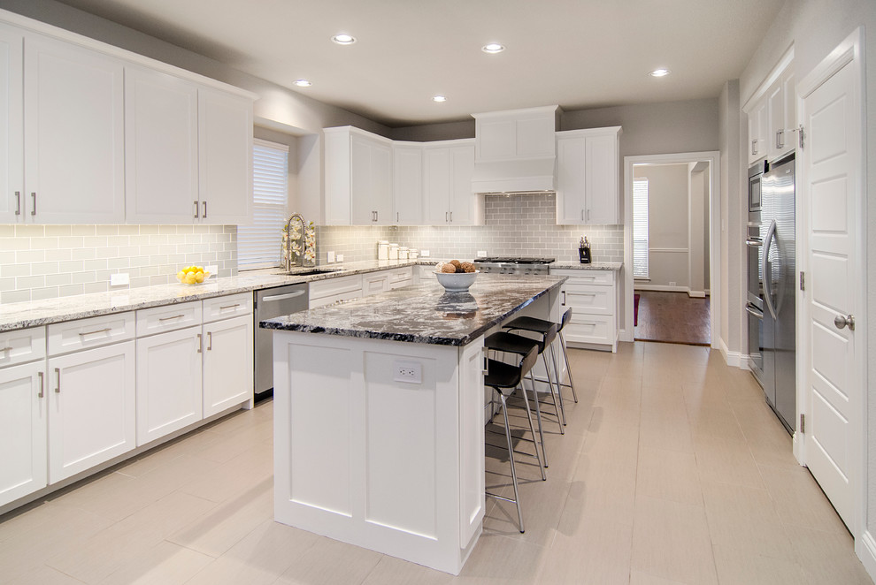 This is an example of a mid-sized modern u-shaped eat-in kitchen in Dallas with an undermount sink, shaker cabinets, white cabinets, granite benchtops, grey splashback, ceramic splashback, stainless steel appliances, medium hardwood floors and with island.