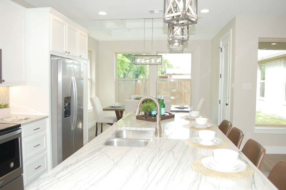 This is an example of a mid-sized traditional single-wall eat-in kitchen in Dallas with an undermount sink, recessed-panel cabinets, white cabinets, quartzite benchtops, beige splashback, mosaic tile splashback, stainless steel appliances, medium hardwood floors, with island, brown floor and beige benchtop.