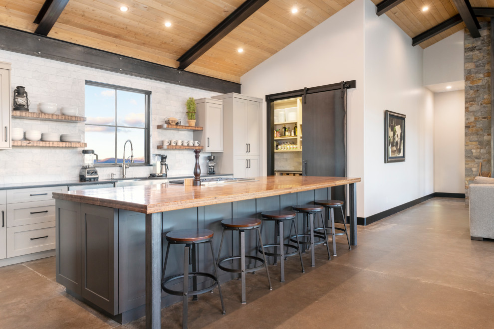 Inspiration for a large country u-shaped open plan kitchen in Denver with a farmhouse sink, shaker cabinets, white splashback, concrete floors, with island, brown floor, grey cabinets, wood benchtops, marble splashback, stainless steel appliances and brown benchtop.