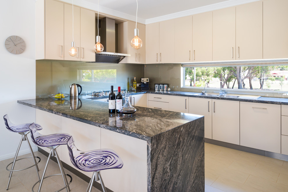 This is an example of a small contemporary u-shaped eat-in kitchen in Perth with a double-bowl sink, flat-panel cabinets, beige cabinets, marble benchtops, grey splashback, glass sheet splashback, stainless steel appliances and porcelain floors.