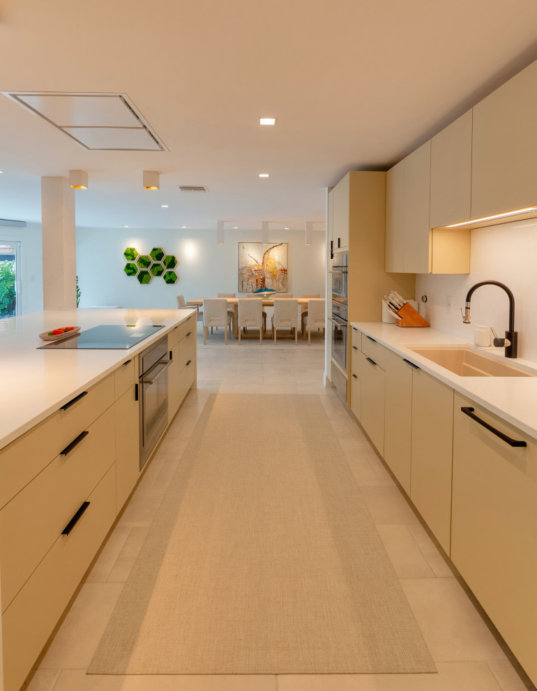 Inspiration for a large modern galley porcelain tile, beige floor and tray ceiling eat-in kitchen remodel in Tampa with an undermount sink, flat-panel cabinets, beige cabinets, quartz countertops, white backsplash, quartz backsplash, stainless steel appliances, an island and white countertops