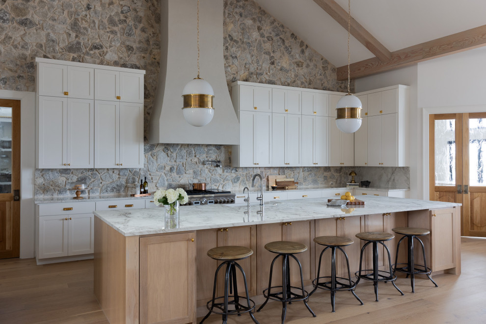 Inspiration for a huge transitional u-shaped light wood floor, beige floor and exposed beam open concept kitchen remodel in Austin with a farmhouse sink, recessed-panel cabinets, beige cabinets, multicolored backsplash, stone tile backsplash, stainless steel appliances, an island and white countertops