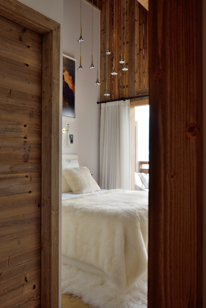 Large contemporary bedroom in Lyon with light hardwood floors, wood and wood walls.