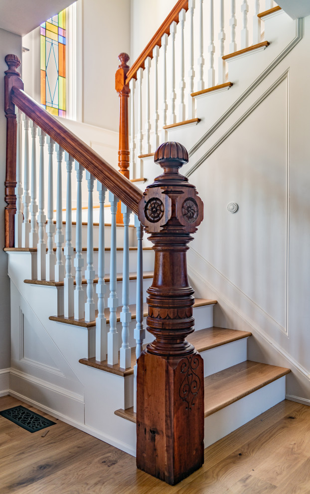 Diseño de escalera tradicional con escalones de madera, contrahuellas de madera pintada y barandilla de madera