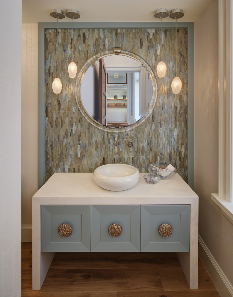 Mid-sized beach style powder room in Miami with blue cabinets, multi-coloured tile, a vessel sink, furniture-like cabinets, mosaic tile, marble benchtops, medium hardwood floors and white benchtops.