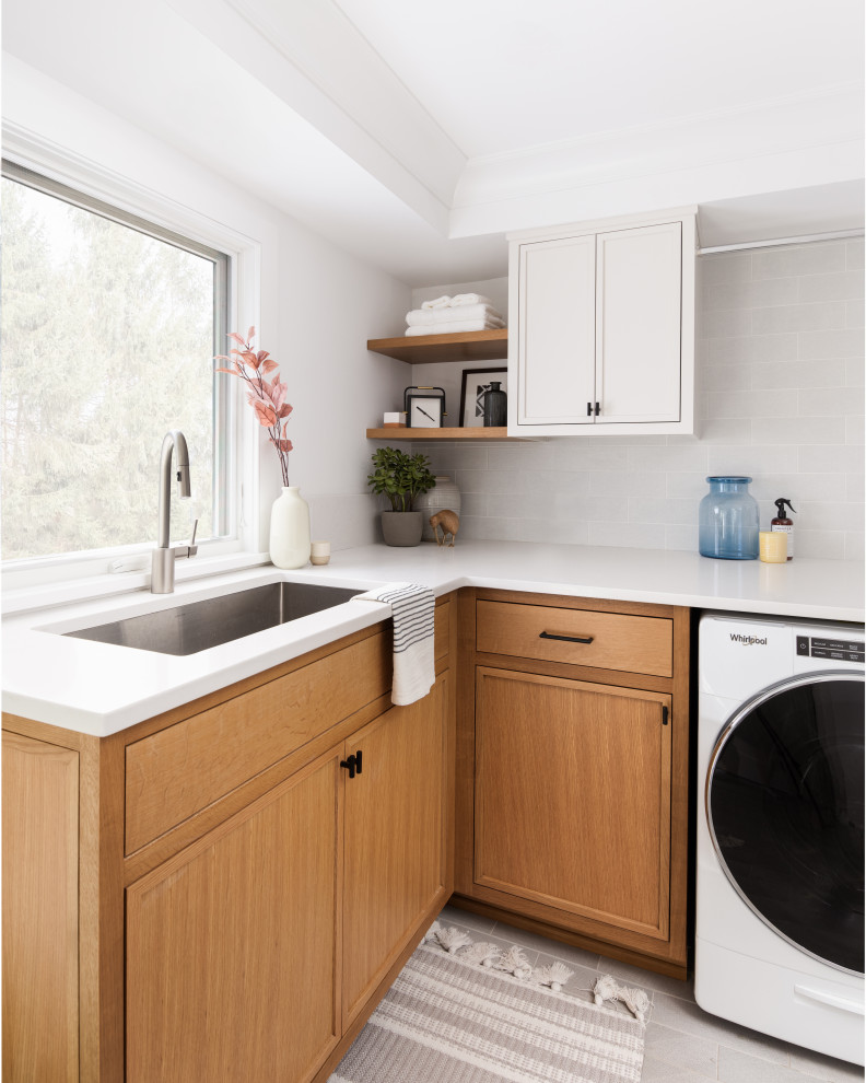 Photo of a medium sized classic l-shaped utility room in New York with a built-in sink, beaded cabinets, white cabinets, composite countertops, white walls, a side by side washer and dryer, grey floors and white worktops.