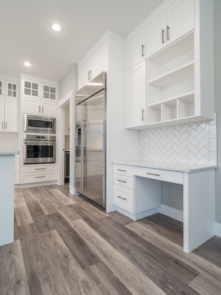 Inspiration for a mid-sized traditional u-shaped eat-in kitchen in Edmonton with a double-bowl sink, recessed-panel cabinets, white cabinets, quartzite benchtops, white splashback, subway tile splashback, stainless steel appliances, vinyl floors, with island and multi-coloured floor.