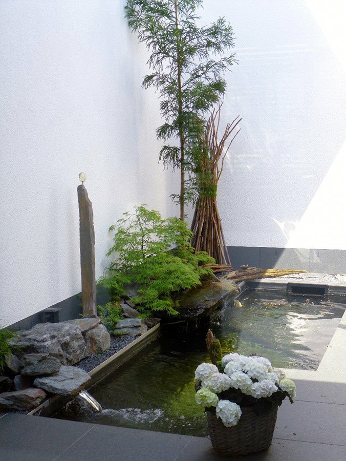 Inspiration for a small asian partial sun garden in Bremen with a water feature and natural stone pavers.