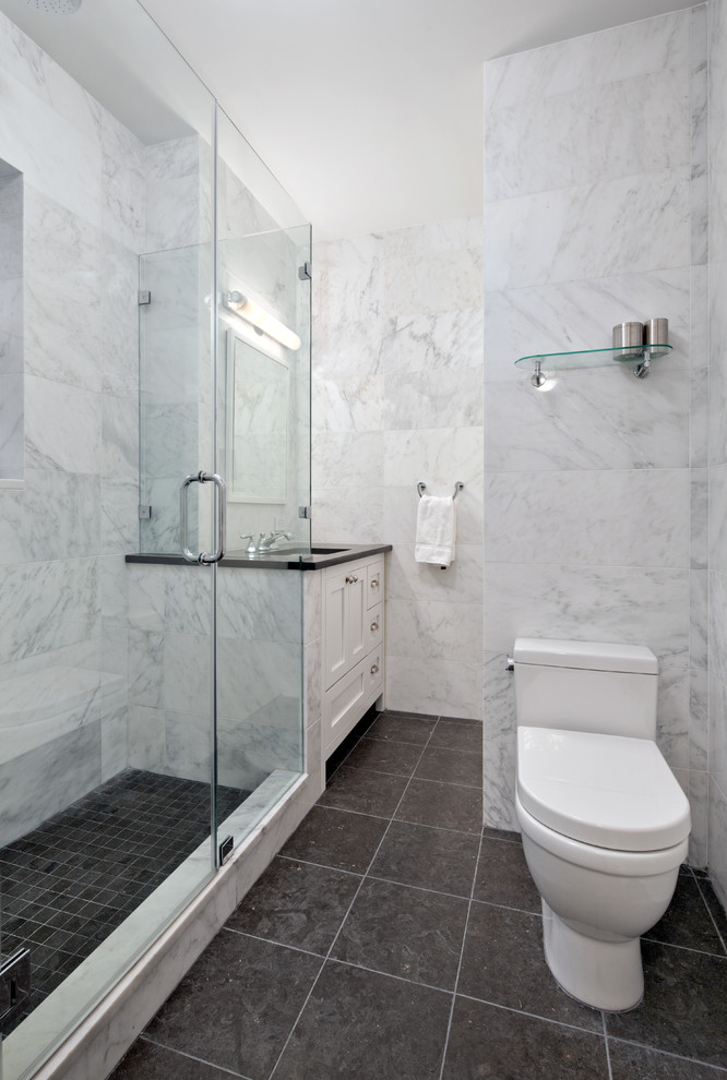 Corner shower - small transitional 3/4 black tile and glass tile porcelain tile corner shower idea with shaker cabinets, white cabinets, a one-piece toilet, white walls and granite countertops