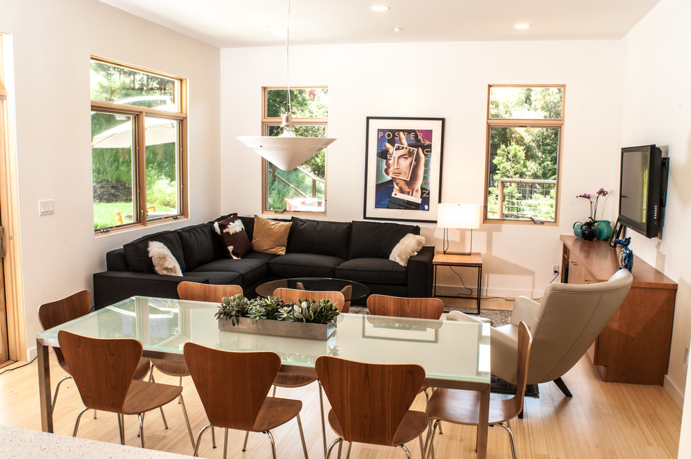 This is an example of a mid-sized modern enclosed family room in San Francisco with white walls, light hardwood floors, no fireplace and a freestanding tv.
