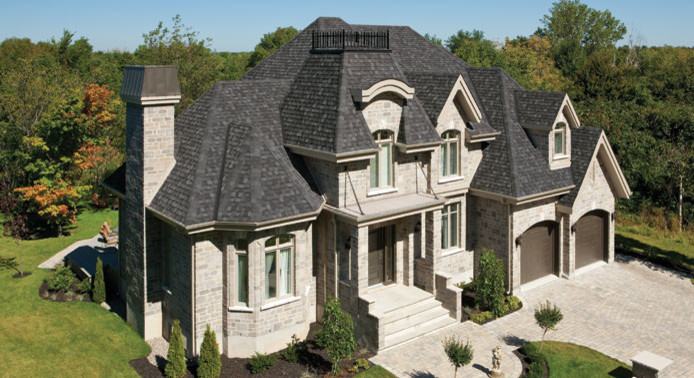 Design ideas for a mid-sized traditional two-storey grey house exterior in Calgary with stone veneer and a clipped gable roof.