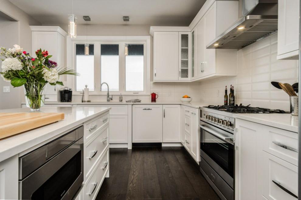 Example of a mid-sized transitional l-shaped dark wood floor and brown floor open concept kitchen design in Ottawa with an undermount sink, shaker cabinets, white cabinets, quartz countertops, white backsplash, subway tile backsplash, stainless steel appliances, an island and white countertops
