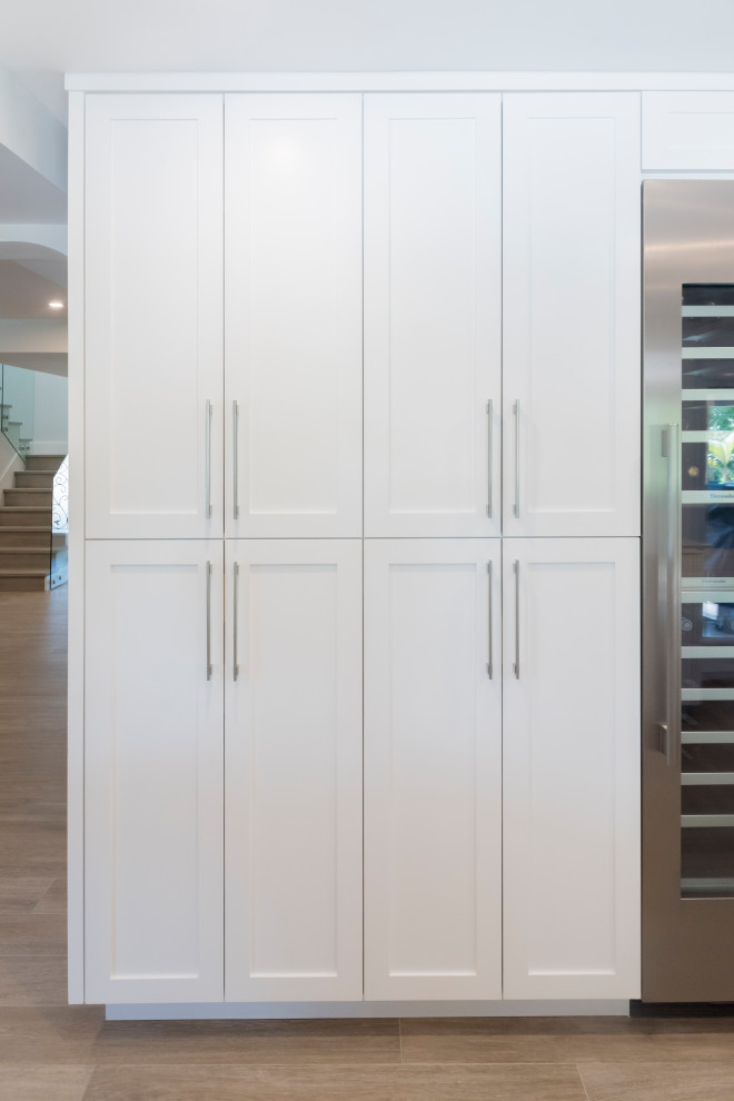 Kitchen pantry - mid-sized transitional galley light wood floor kitchen pantry idea in Miami with an undermount sink, shaker cabinets, white cabinets, quartz countertops, white backsplash, marble backsplash, stainless steel appliances and white countertops