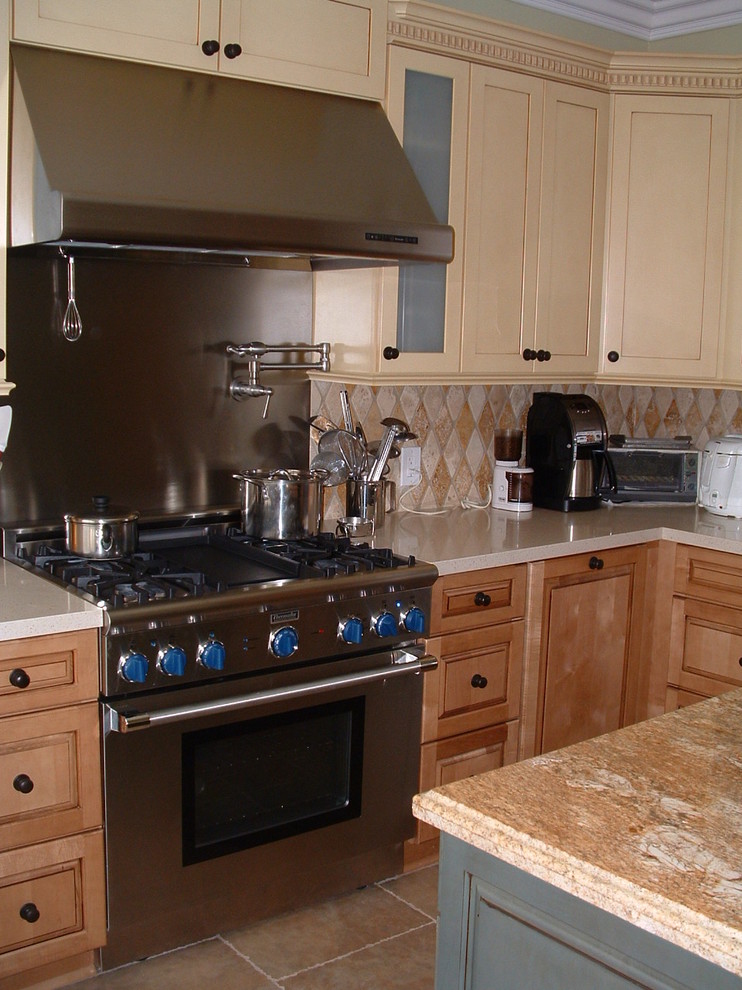 Example of a mid-sized transitional u-shaped travertine floor eat-in kitchen design in Orange County with a farmhouse sink, shaker cabinets, yellow cabinets, quartz countertops, multicolored backsplash, stone tile backsplash, stainless steel appliances and an island